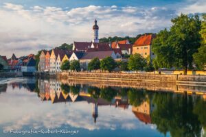 Die Altstadt von Landsberg am Lech spiegelt sich in der glatten Oberlfäche des Lechs