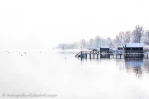 Verschneite Bootshäuser im Winter am Ammersee bei Holzhausen